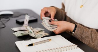 Kobieta liczy banknoty, które trzyma w ręce. Możliwe, że liczy ile wyniesie jej prowadzenie sprawy frankowej.